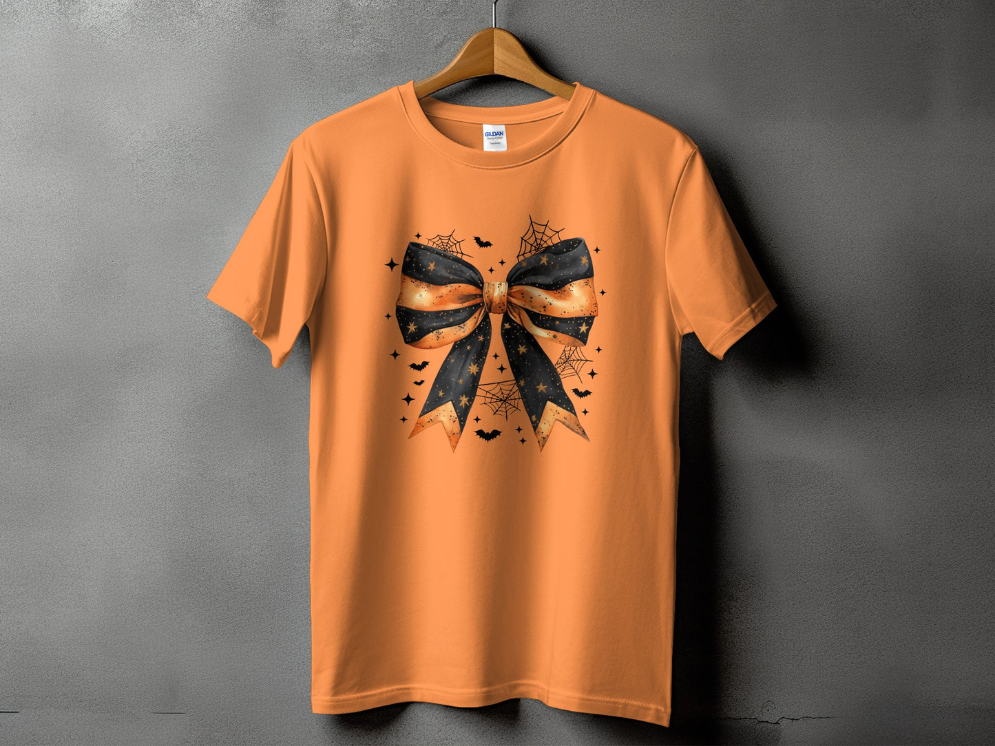 Orange t-shirt with a black and orange Halloween bow graphic and spooky accents.