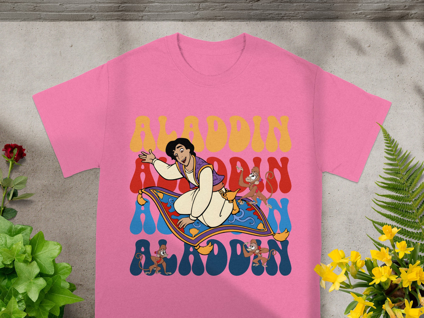 Pink t-shirt with Aladdin, Abu, and Magic Carpet graphic.
