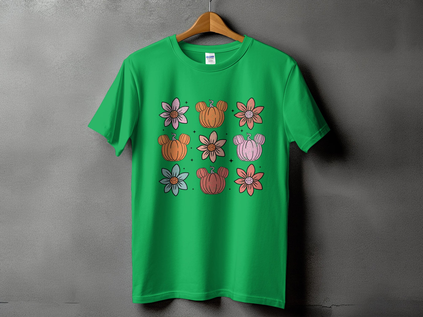 Green t-shirt with floral and pumpkin designs arranged in a grid.