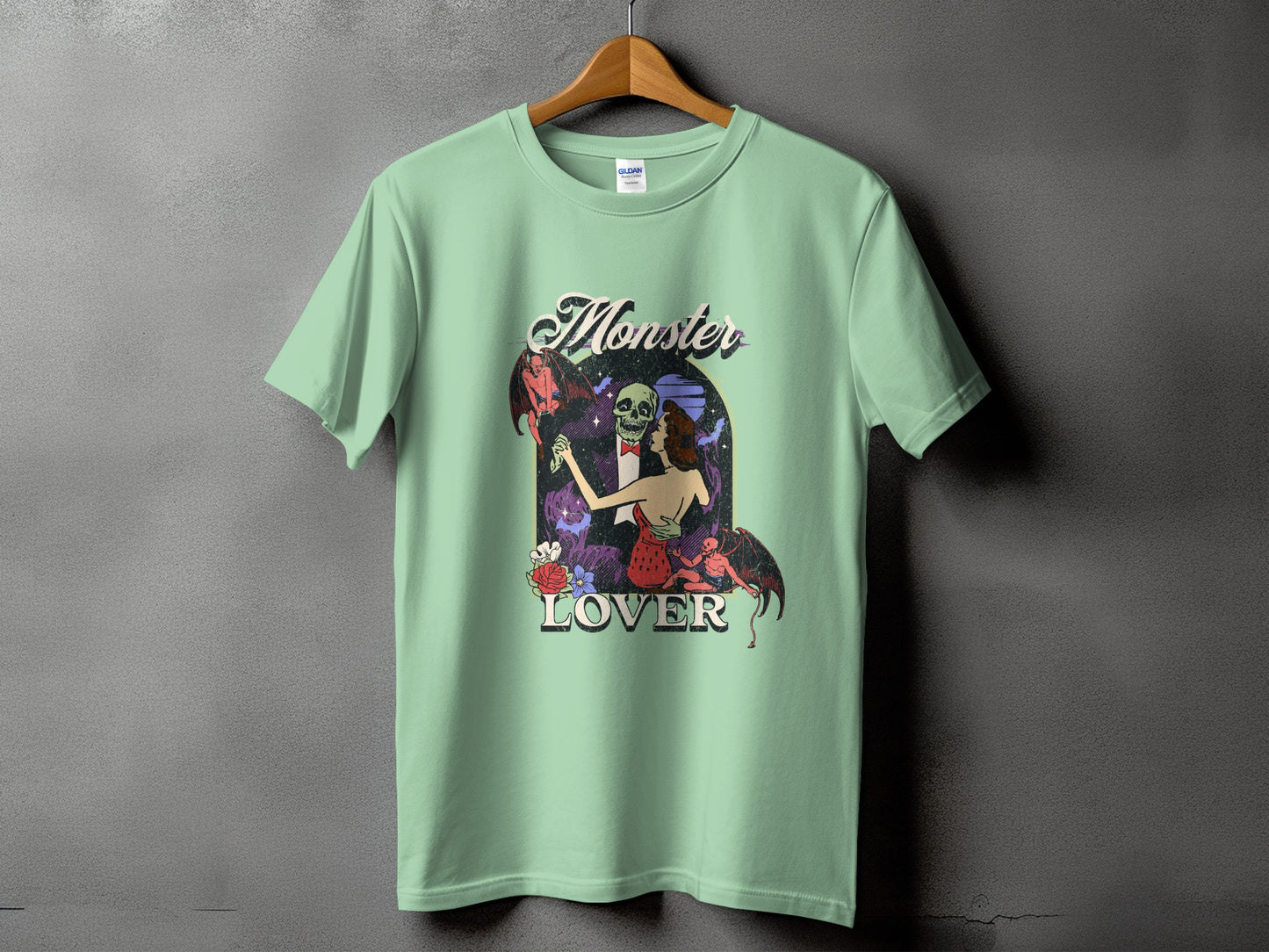 Light green t-shirt with "Monster Lover" text and retro graphic of dancing skeletons and demons.