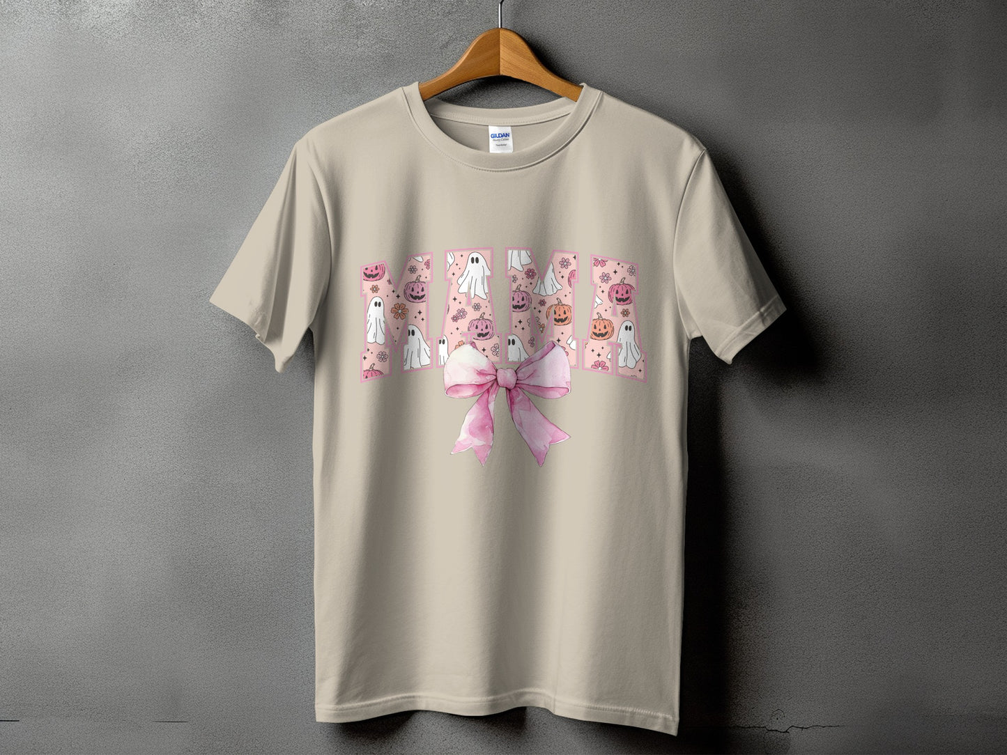 "Mama" text with Halloween ghosts, pumpkins, and flowers, on a tan t-shirt.
