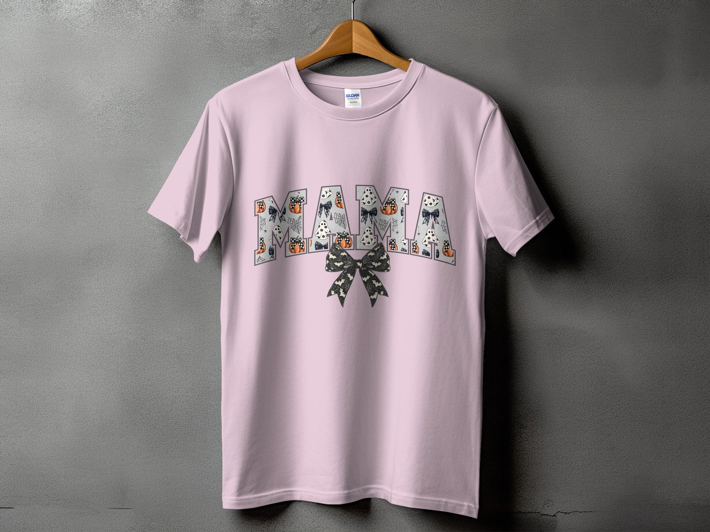 Pink t-shirt with "MAMA" in Halloween-themed letters and a bow.
