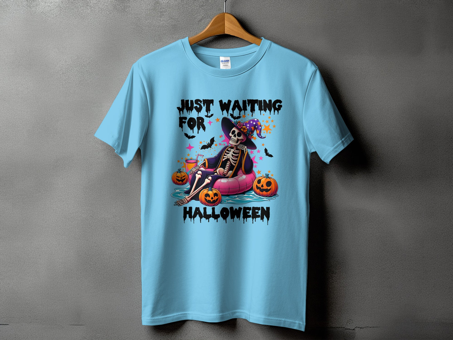 Skeleton on inflatable tube with pumpkins reads "JUST WAITING FOR HALLOWEEN".