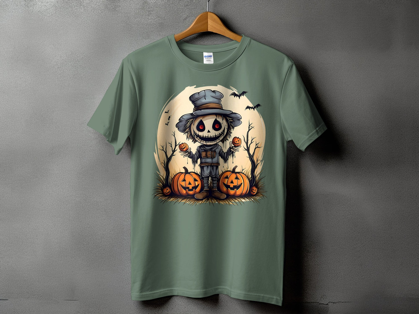Green t-shirt with a cartoon scarecrow holding pumpkins and bats on a moon background.