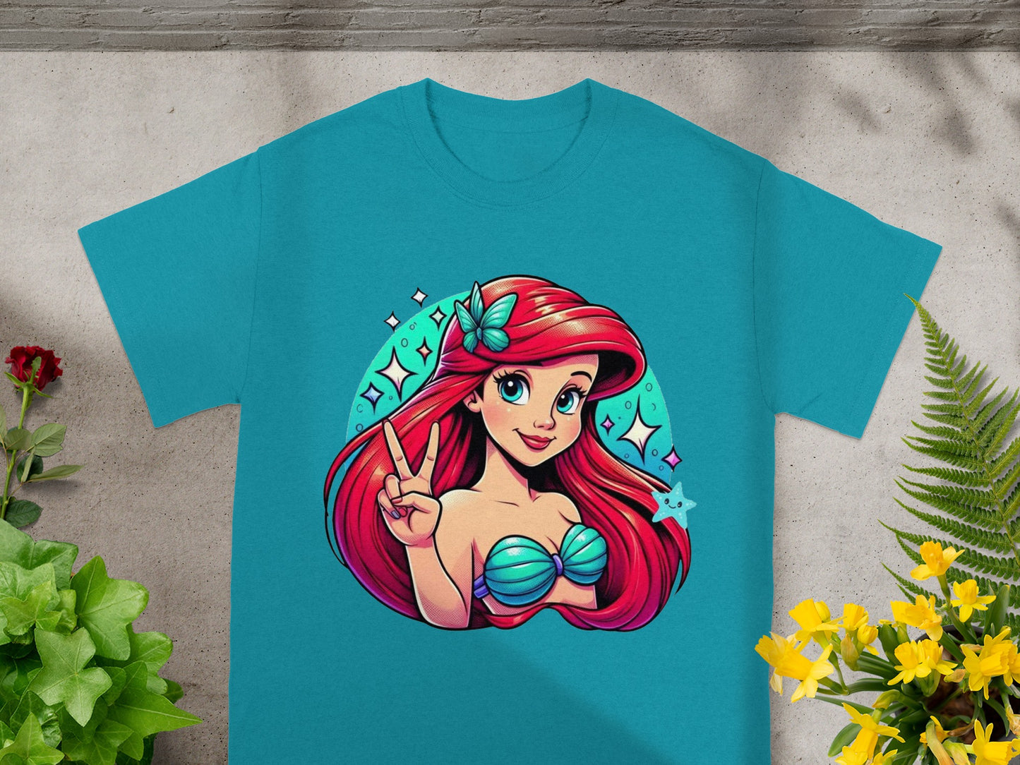Teal t-shirt with cartoon Ariel holding peace sign, surrounded by stars.