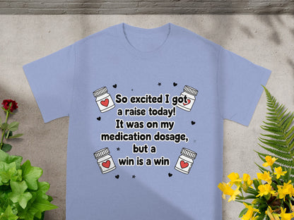 Light blue t-shirt with "So excited I got a raise today! It was on my medication dosage, but a win is a win" text.