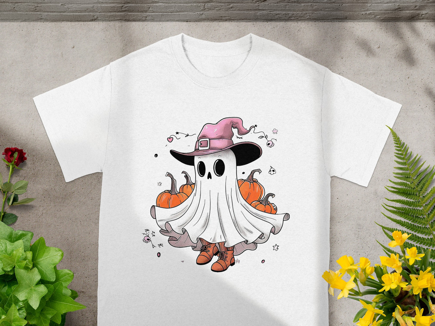 White t-shirt with cartoon ghost in witch hat surrounded by pumpkins.
