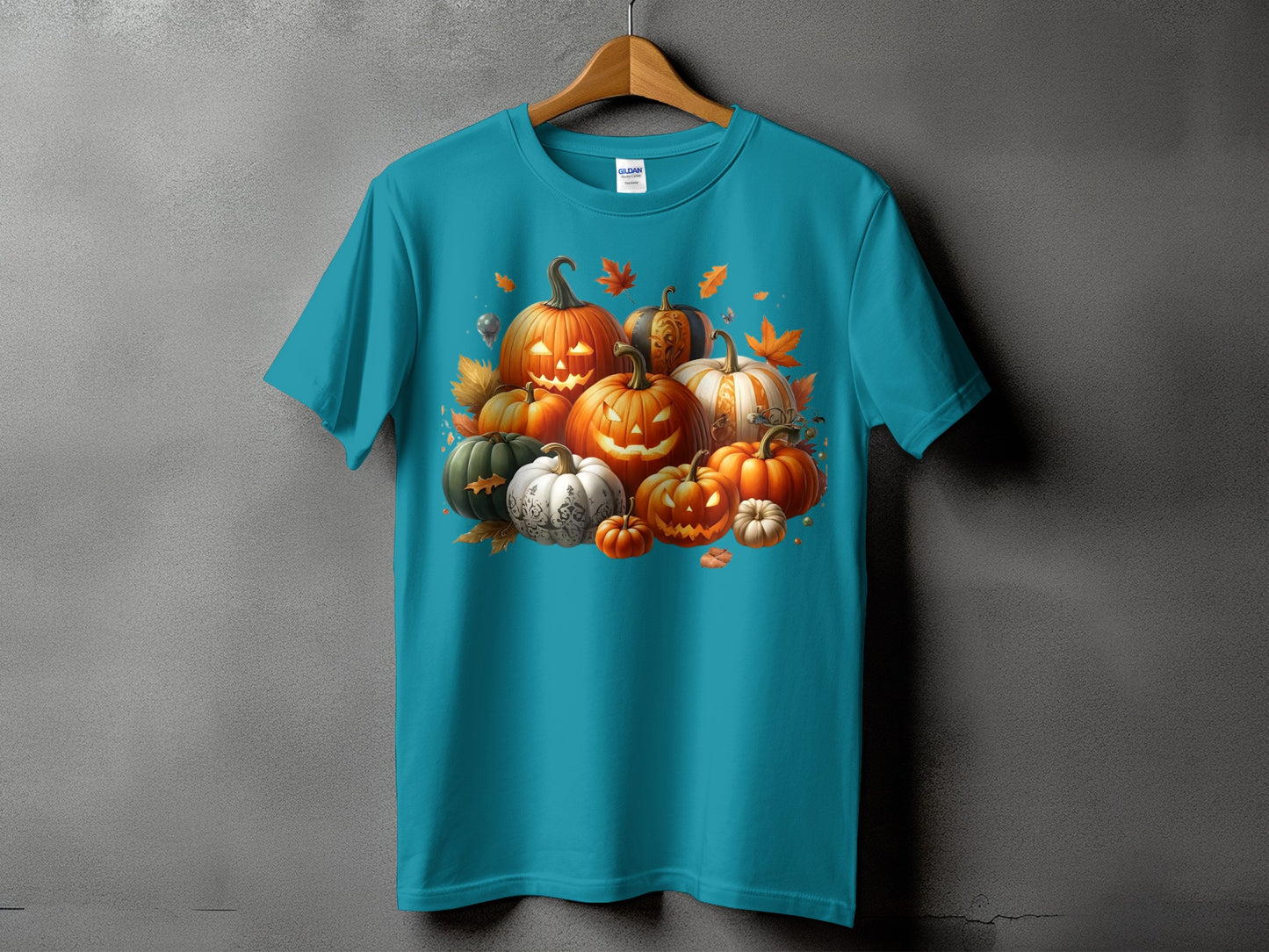 Teal t-shirt with a pile of carved and decorative pumpkins, autumn leaves, and butterflies.