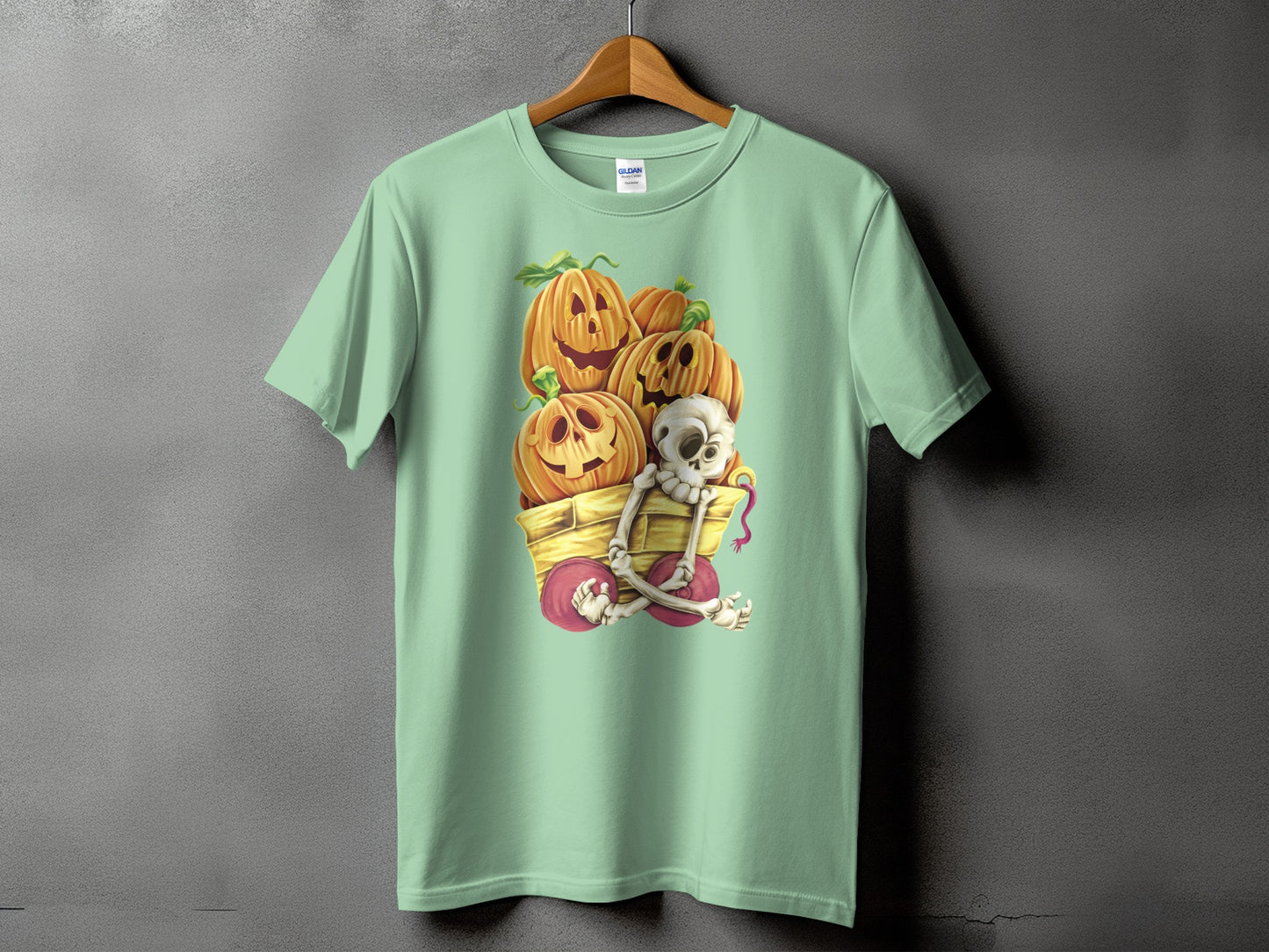 Mint t-shirt with a graphic of carved pumpkins and a skeleton in a wagon.