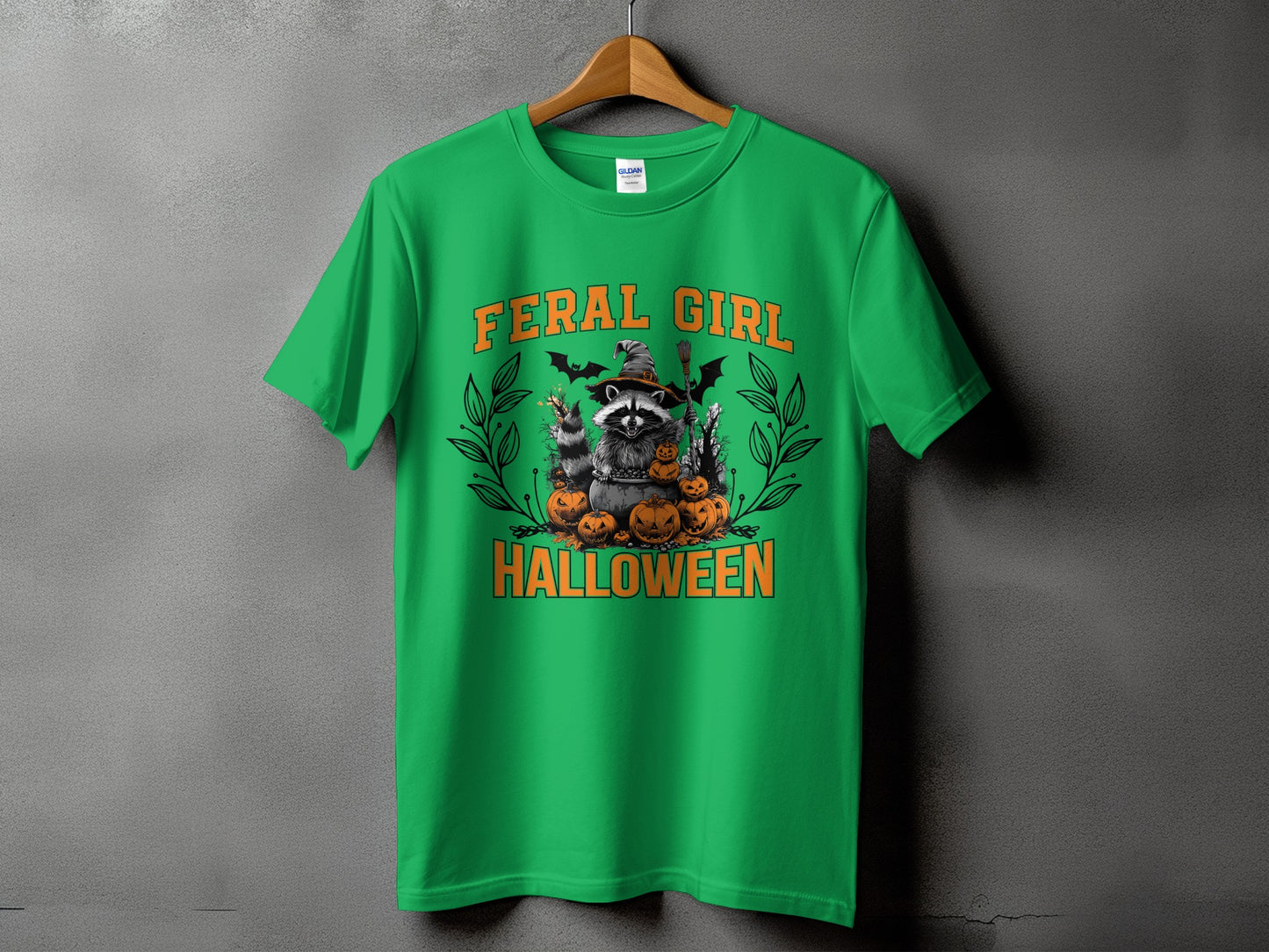 Green t-shirt with Halloween graphic: Feral Girl, raccoon, pumpkins, bats, and broom.