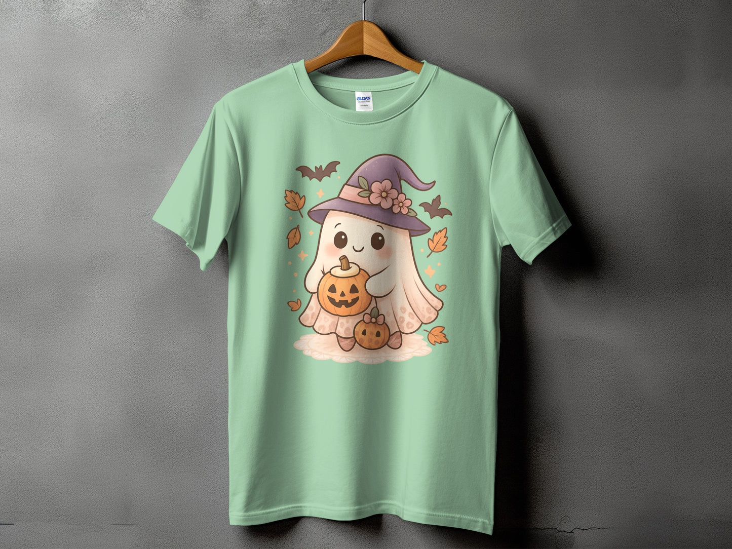 Light green t-shirt with a ghost holding pumpkins and wearing a witch hat.