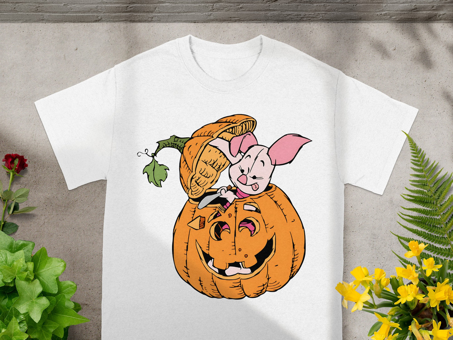 Piglet peeking out of a jack-o'-lantern on a white t-shirt.