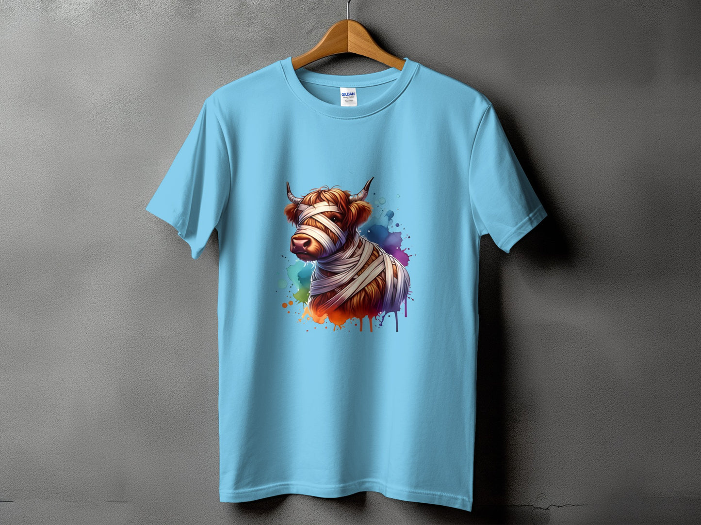 Light blue t-shirt with a Highland cow wrapped in bandages graphic.