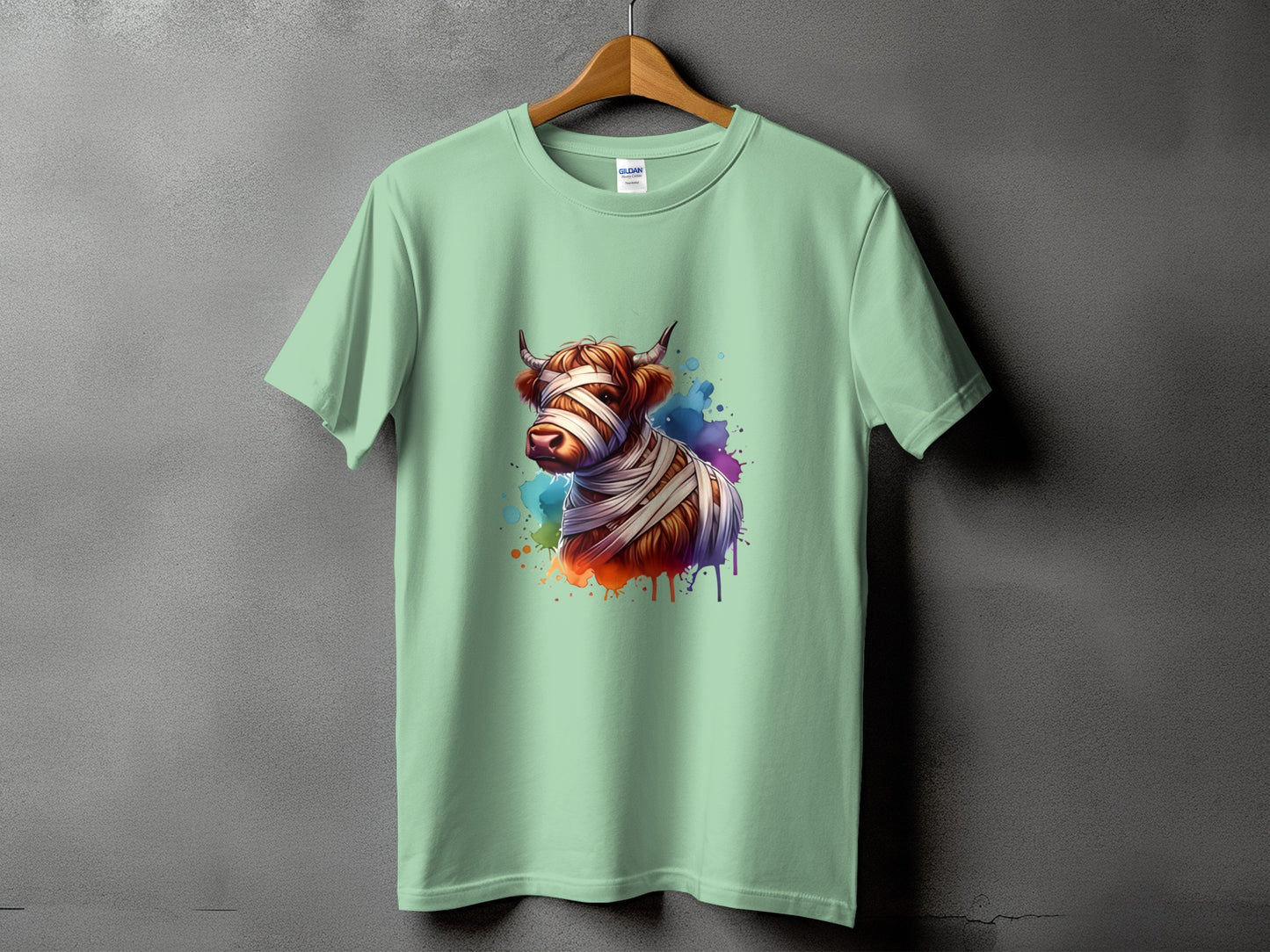 Light green t-shirt with a watercolor Highland cow design wrapped in bandages.
