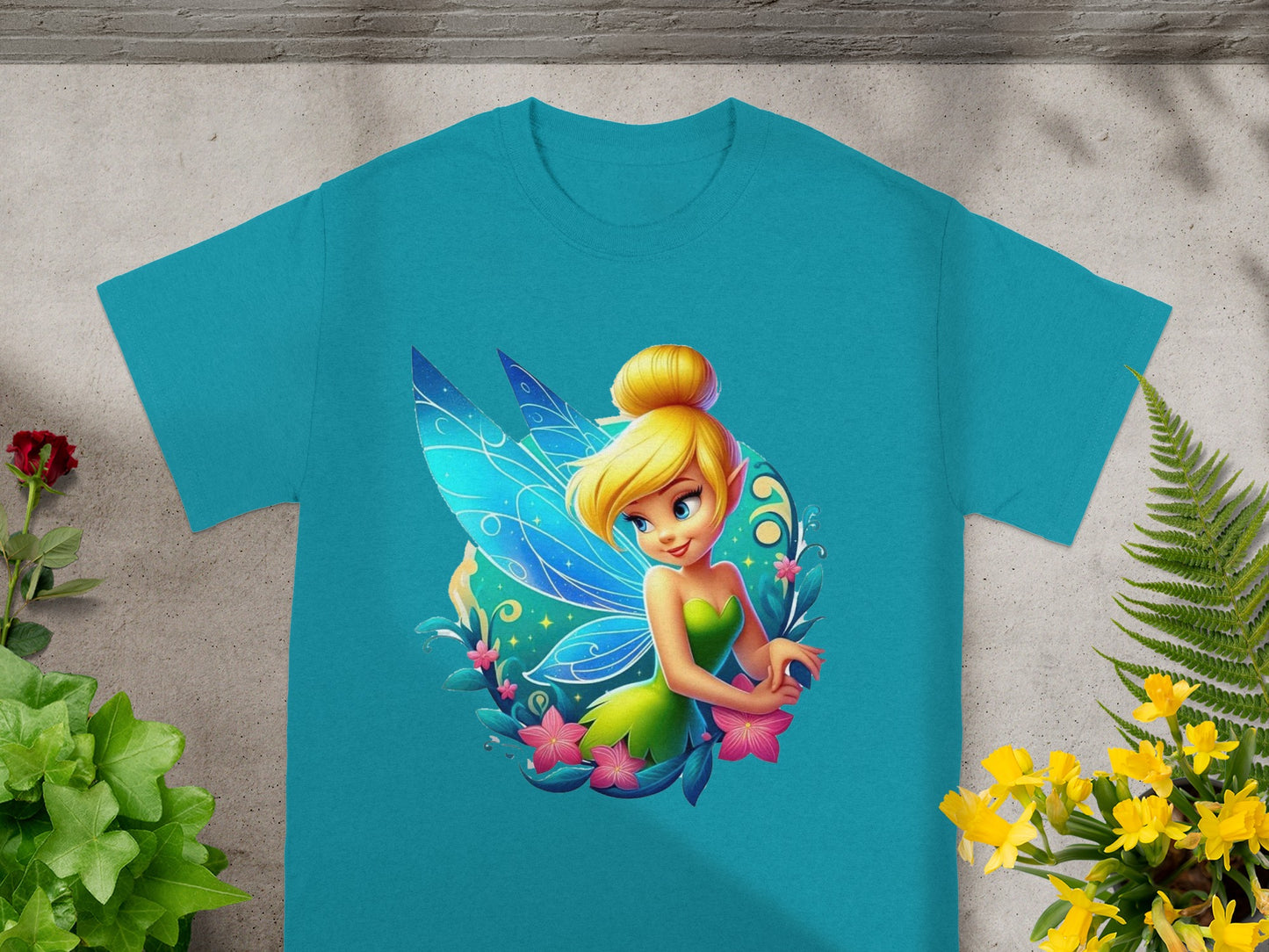 Tinkerbell illustration on a teal t-shirt with floral accents.