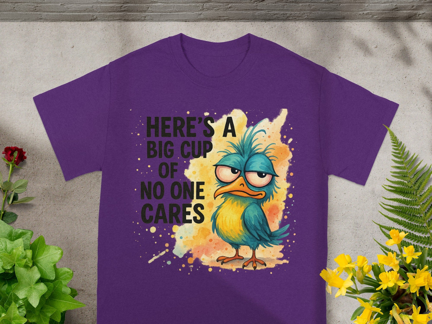 Purple t-shirt with a grumpy bird and text "Here's a big cup of no one cares."