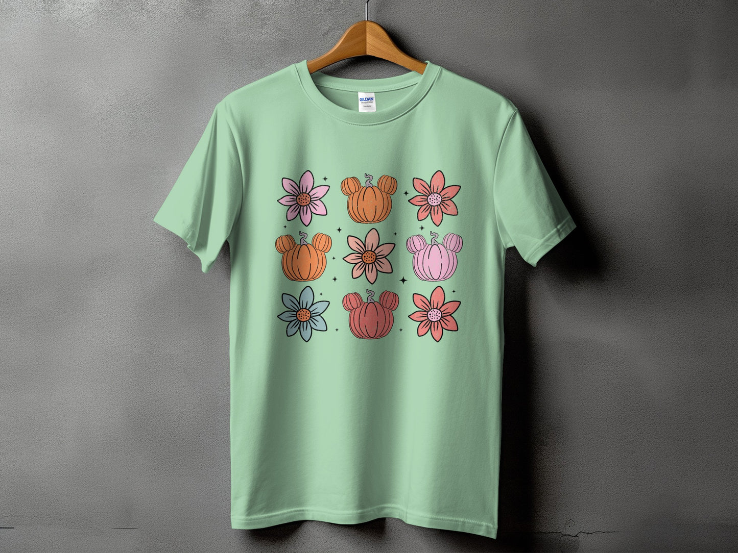 Mint t-shirt with a grid of flowers and Mickey-shaped pumpkins.