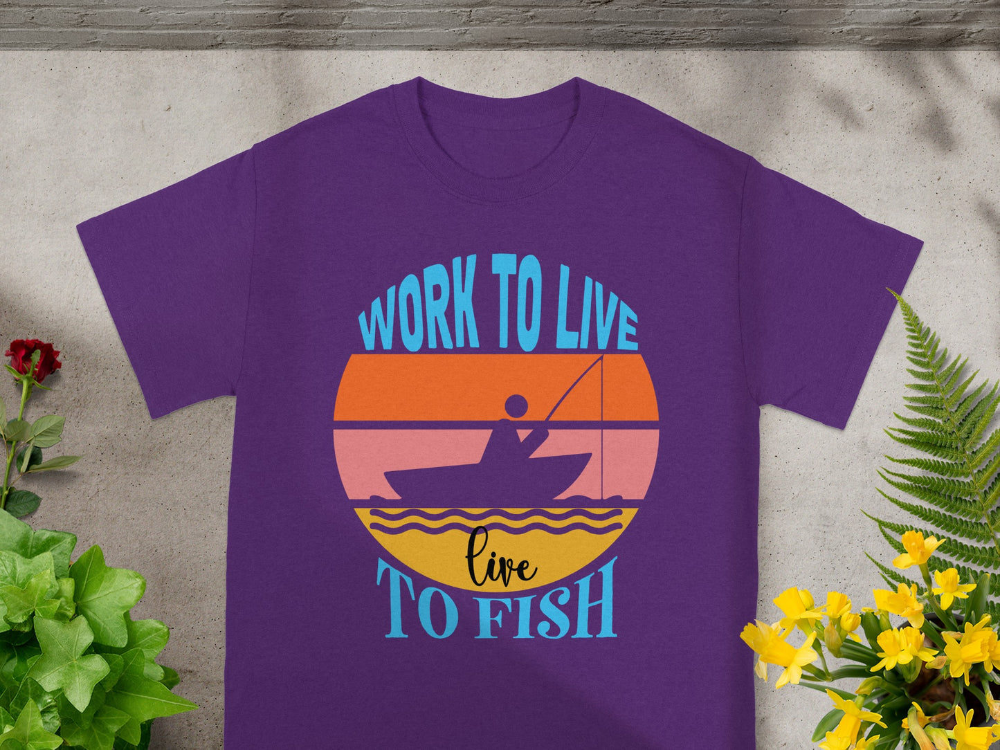 Purple t-shirt with "Work to Live Live to Fish" graphic of sunset and fishing