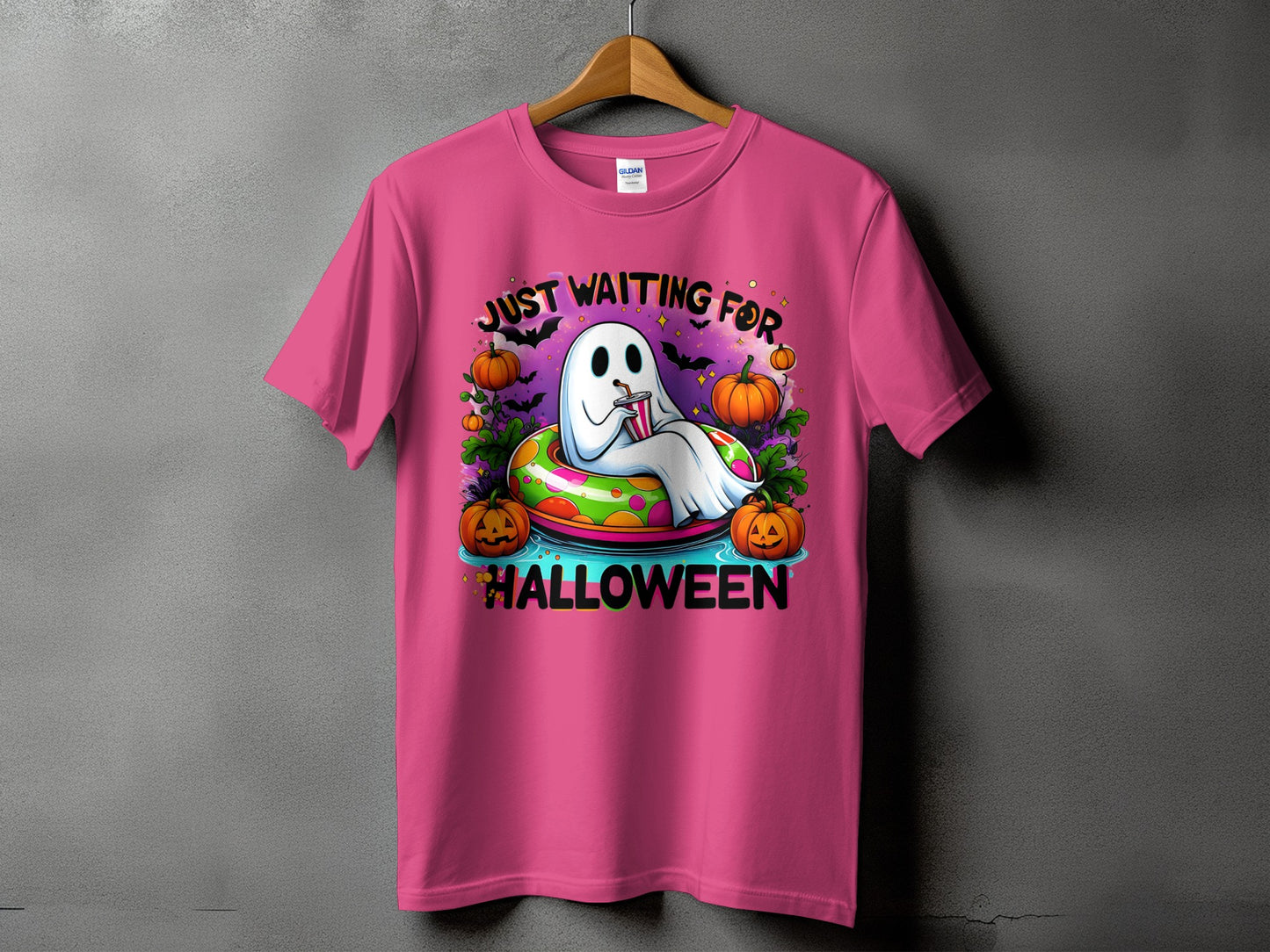 Pink t-shirt with ghost on float surrounded by pumpkins, bats, and text "JUST WAITING FOR HALLOWEEN".