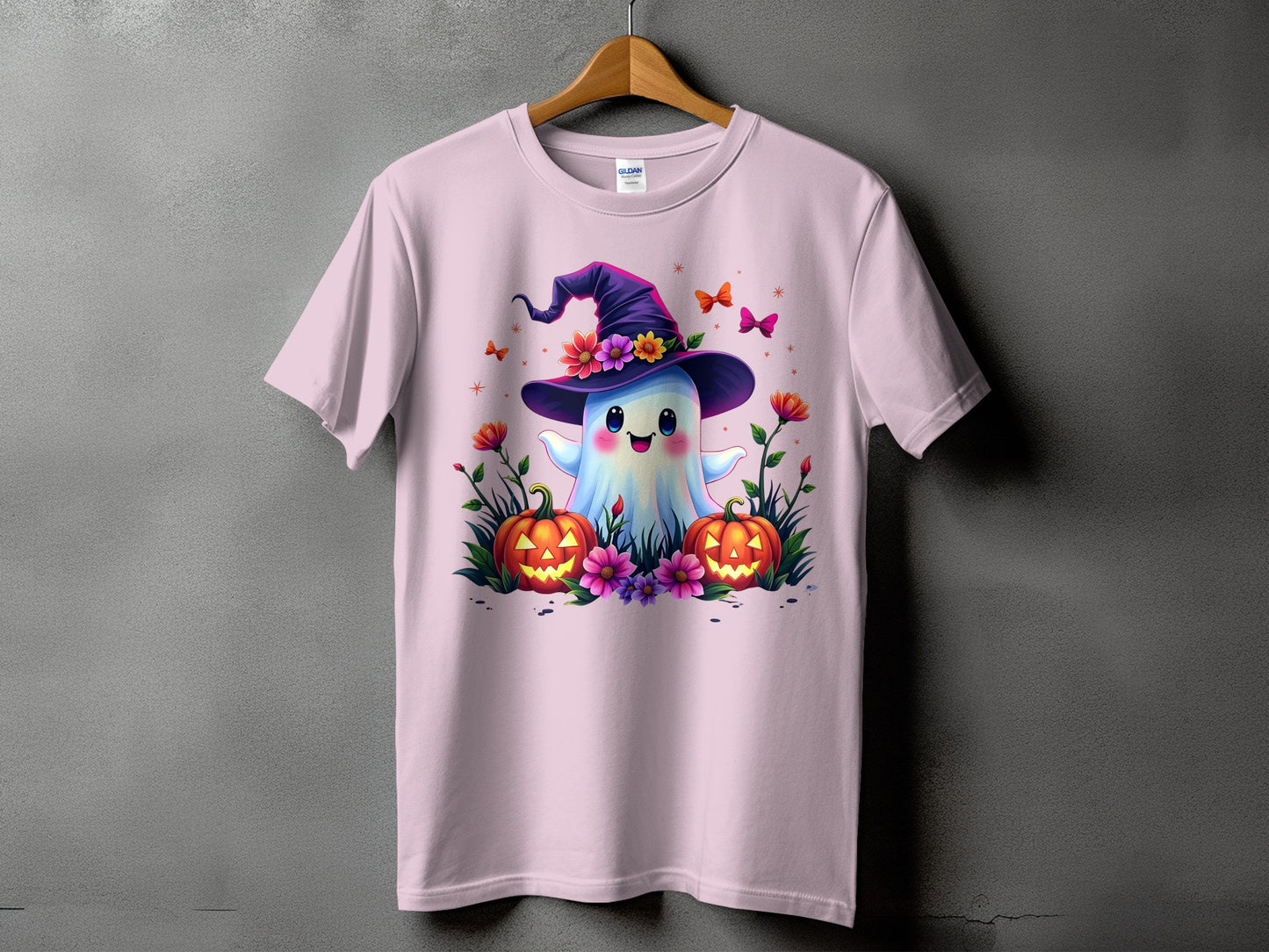 Pink t-shirt with a cute ghost wearing a witch hat and surrounded by pumpkins and flowers.