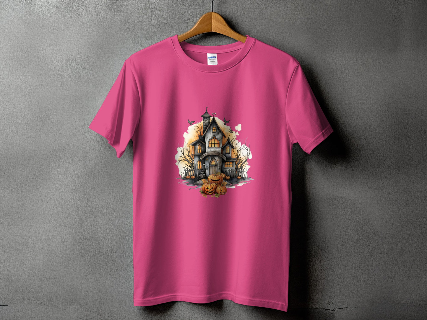 Pink t-shirt with a watercolor haunted house and pumpkins graphic.