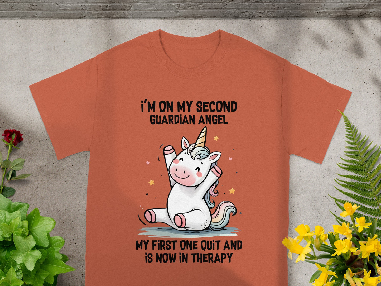 Orange t-shirt with cartoon unicorn and text about guardian angels.