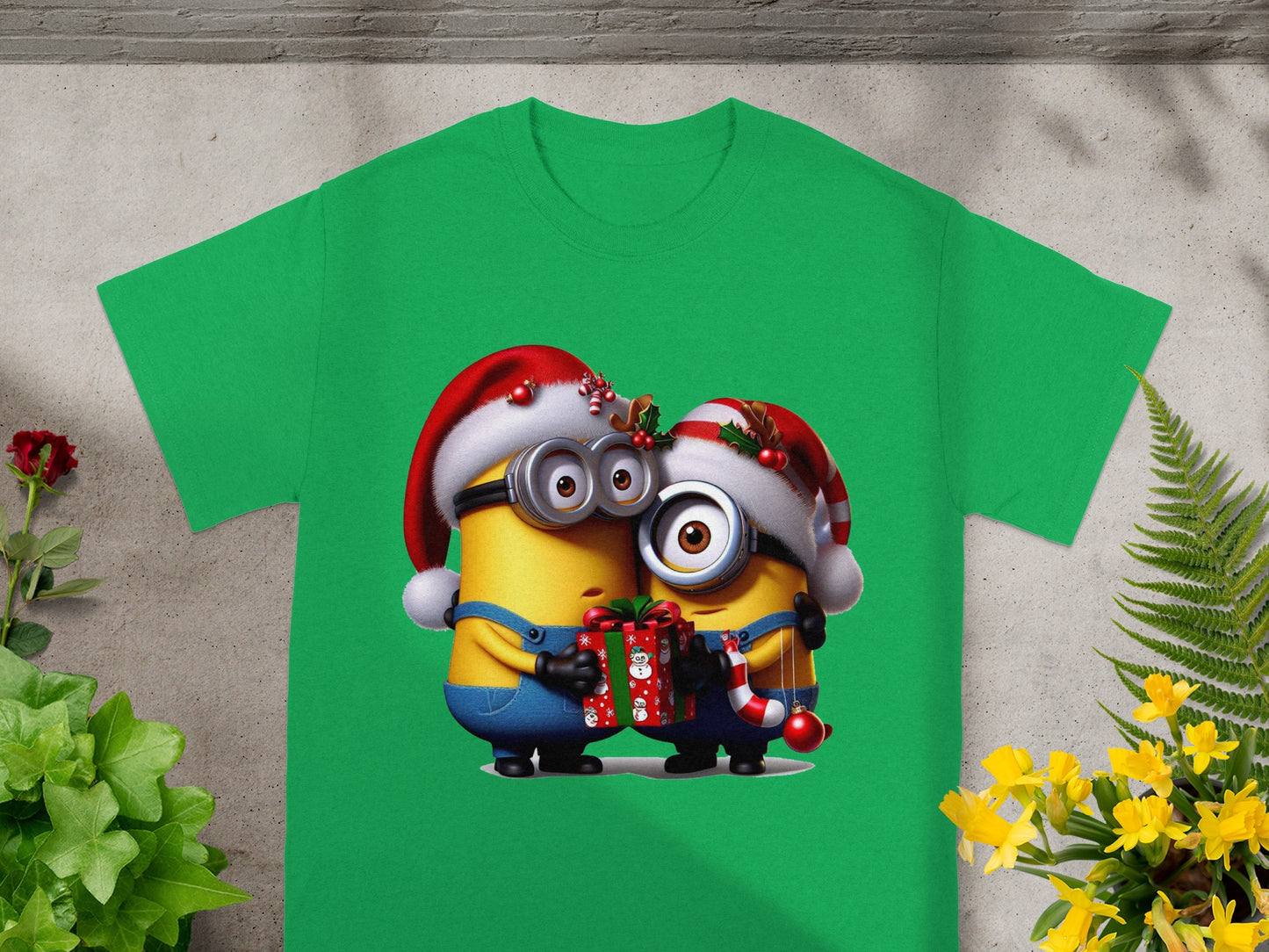 Two Minions wearing Santa hats embrace, holding a Christmas gift and candy cane.