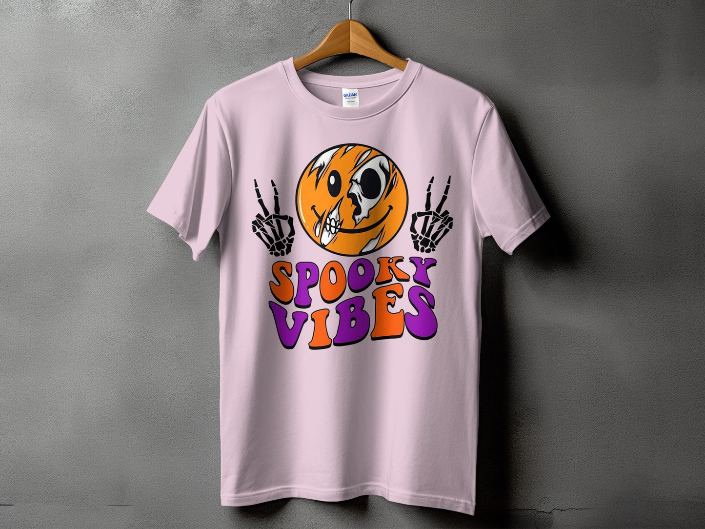 Pink t-shirt with spooky smiley face and skeleton hands, text reads "Spooky Vibes".