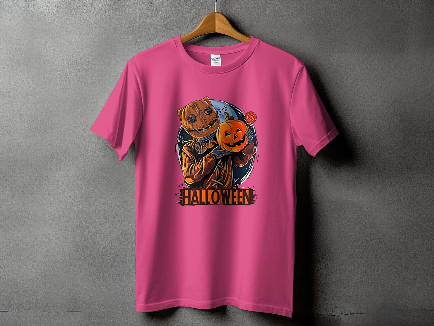 Pink t-shirt with a stitched pumpkin character holding a small pumpkin and candy.