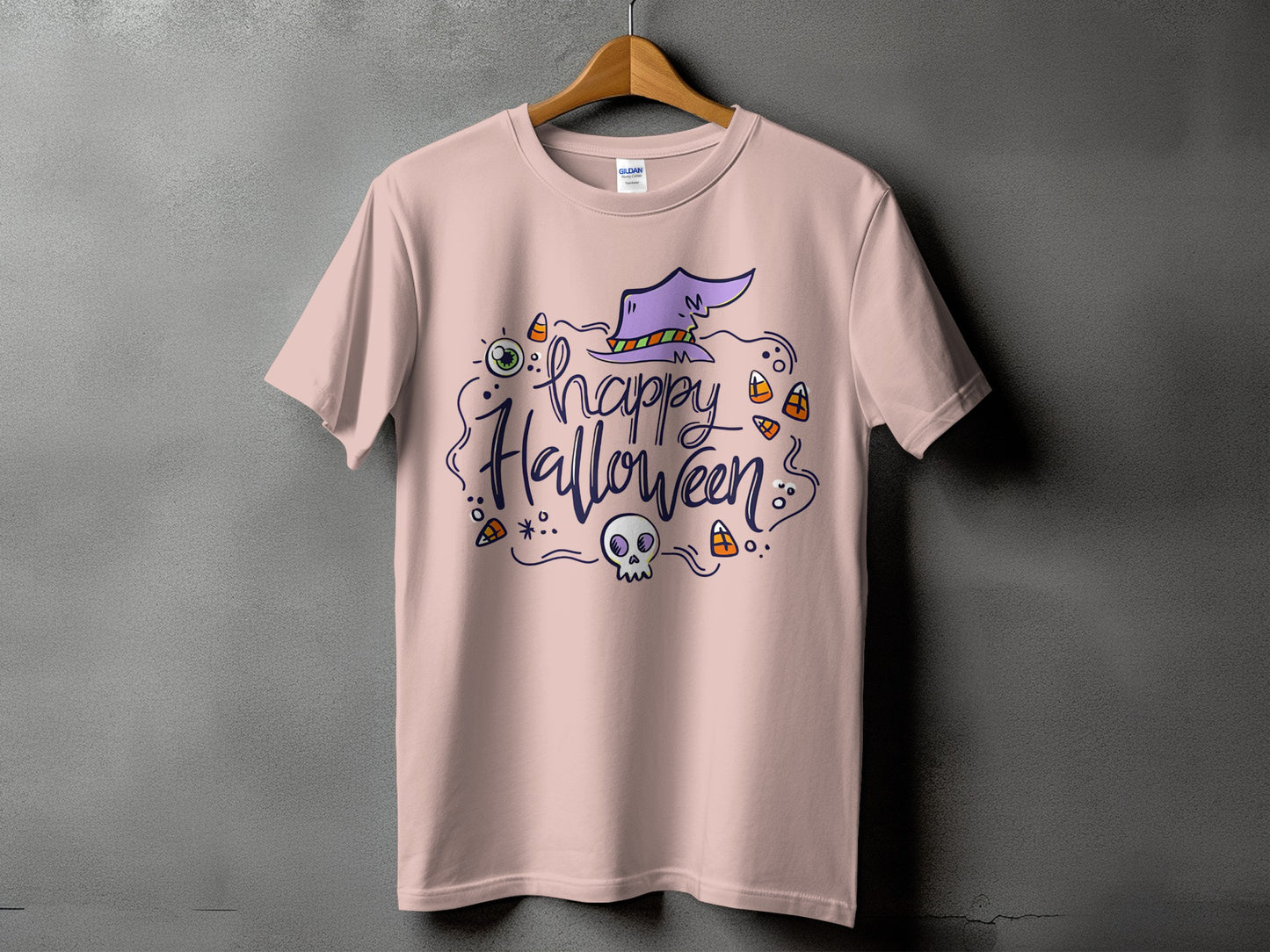 Pink t-shirt with "happy Halloween" text, a witch hat, eyeball, skull, and candy corn.
