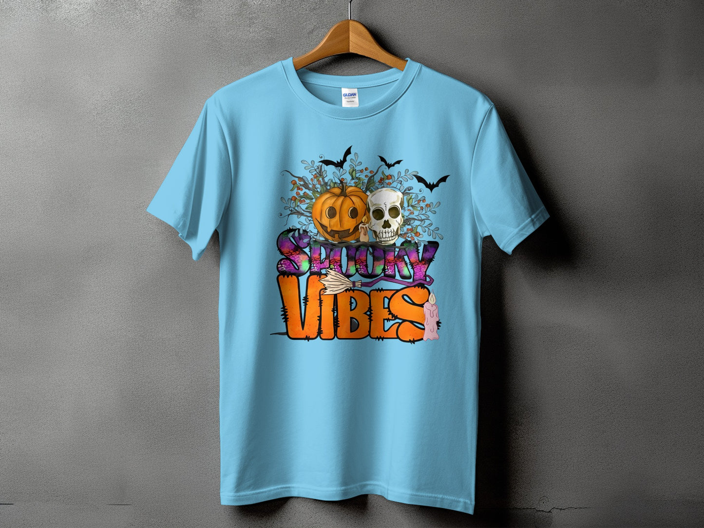 Light blue t-shirt with "Spooky Vibes" text, pumpkin, skull, bats, and candle graphic.