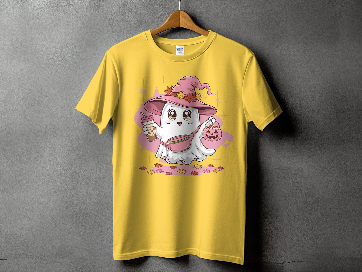 Yellow t-shirt with a cute ghost wearing a pink witch hat, holding a drink and pumpkin.