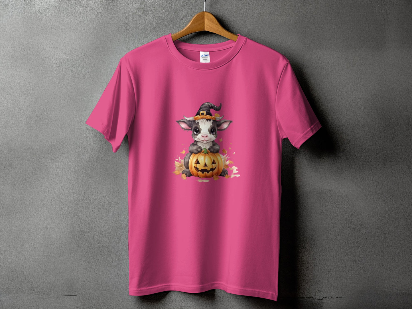 Pink t-shirt with a cute cow wearing a witch hat sitting on a pumpkin.