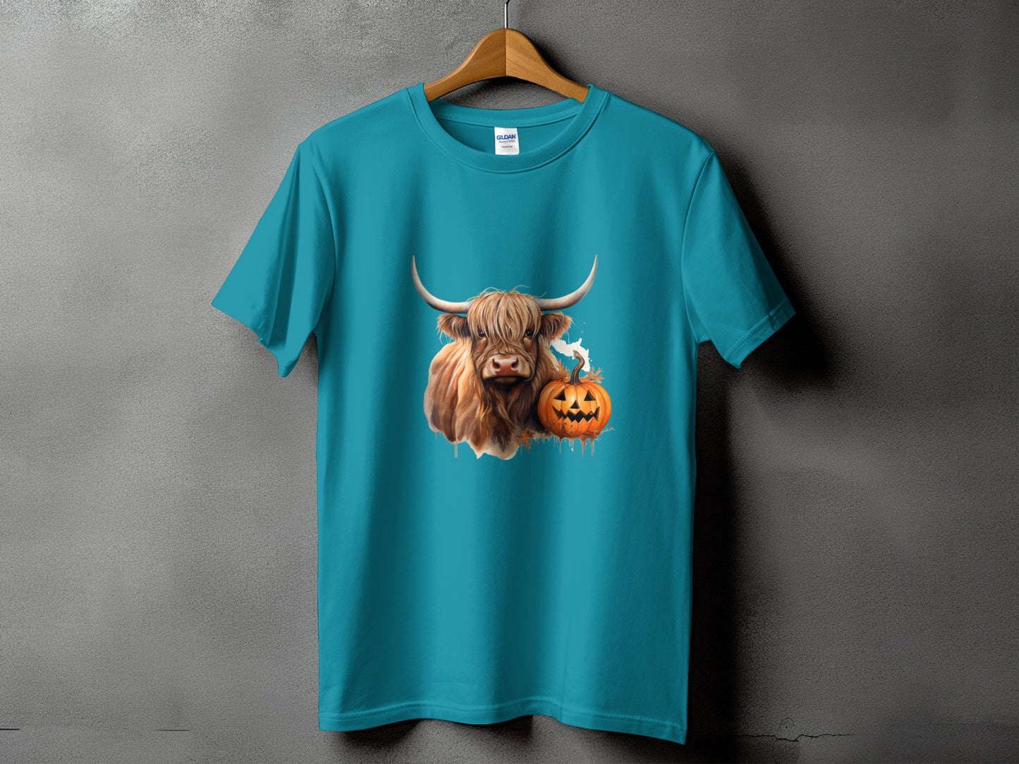 Teal t-shirt with a Highland cow and carved pumpkin Halloween graphic.