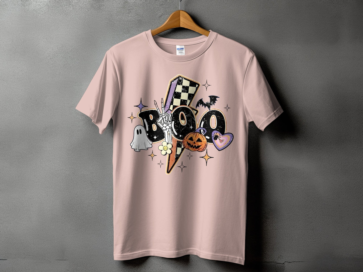 Pink t-shirt with Halloween "BOO" graphic featuring ghost, skeleton hand, pumpkin, and bat.