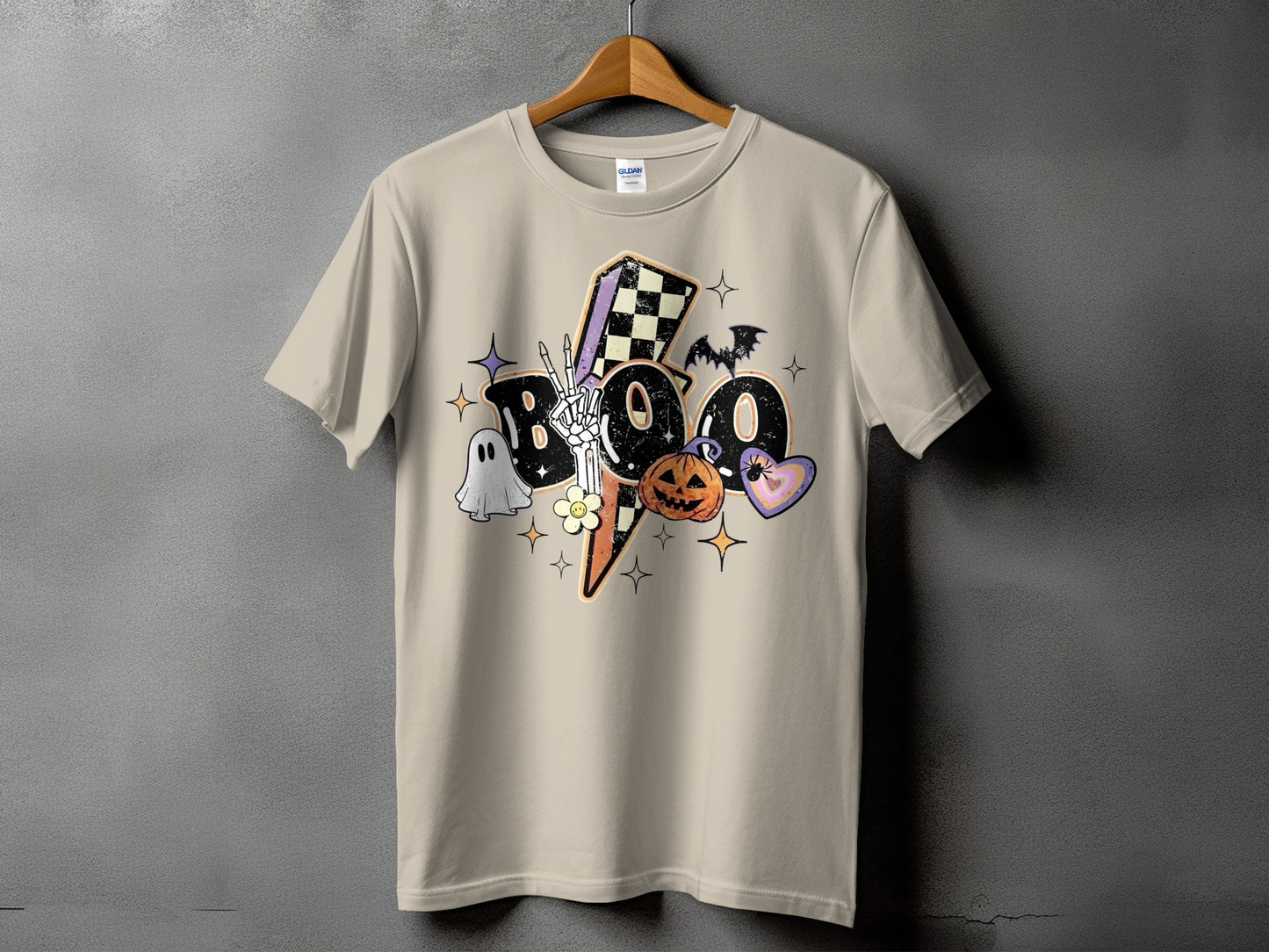 Tan t-shirt with "BOO" text and Halloween graphics like a ghost, pumpkin, and bat.