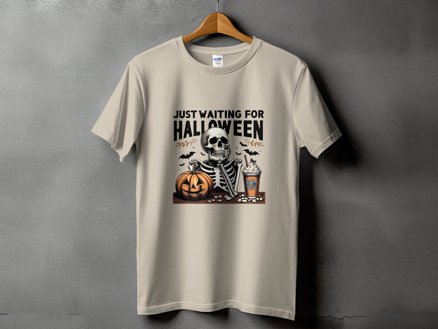 Skeleton with pumpkin and coffee cup on t-shirt, reading "JUST WAITING FOR HALLOWEEN".