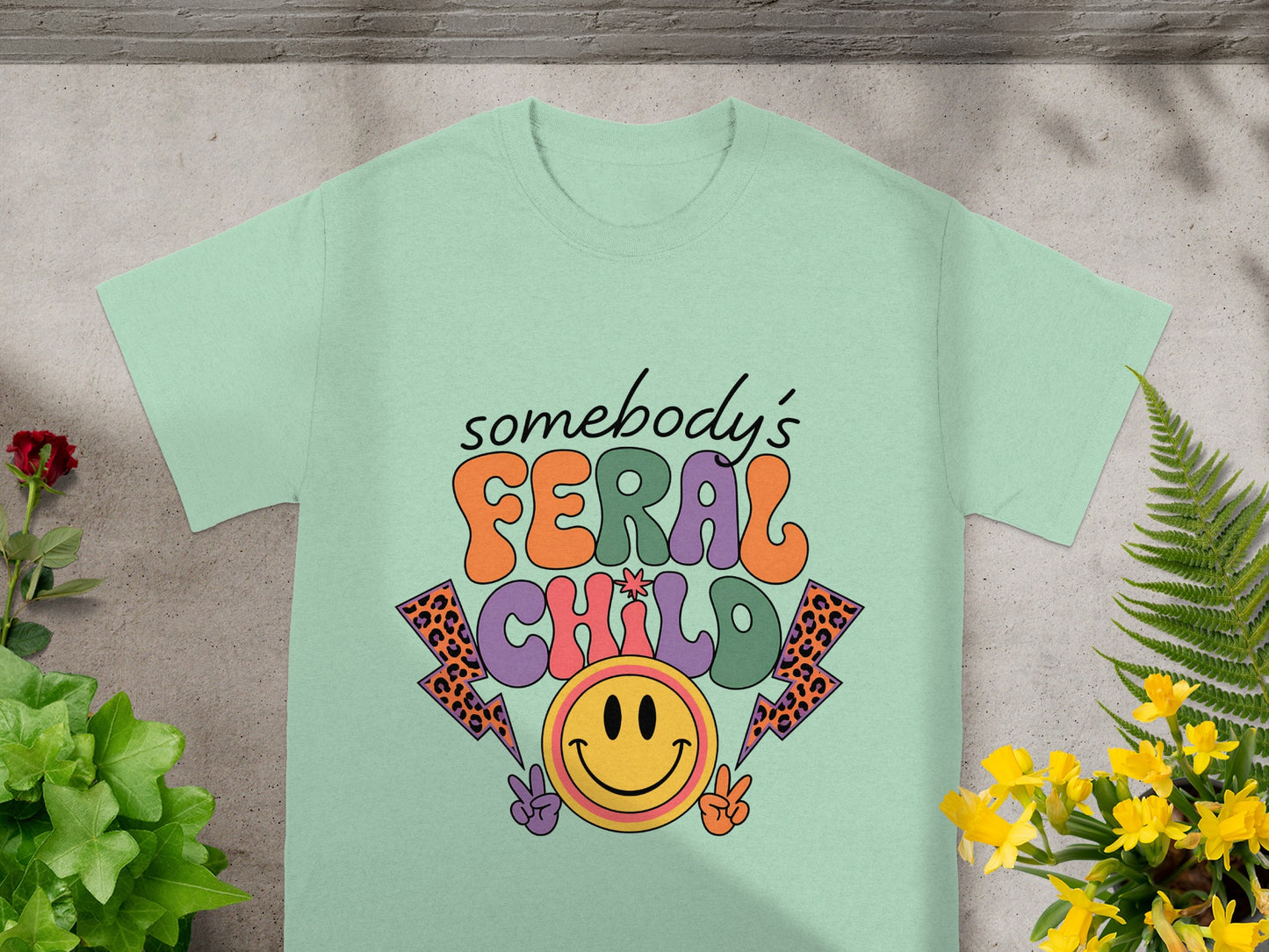 Light green t-shirt with "somebody's FERAL CHILD" graphic and smiley face.