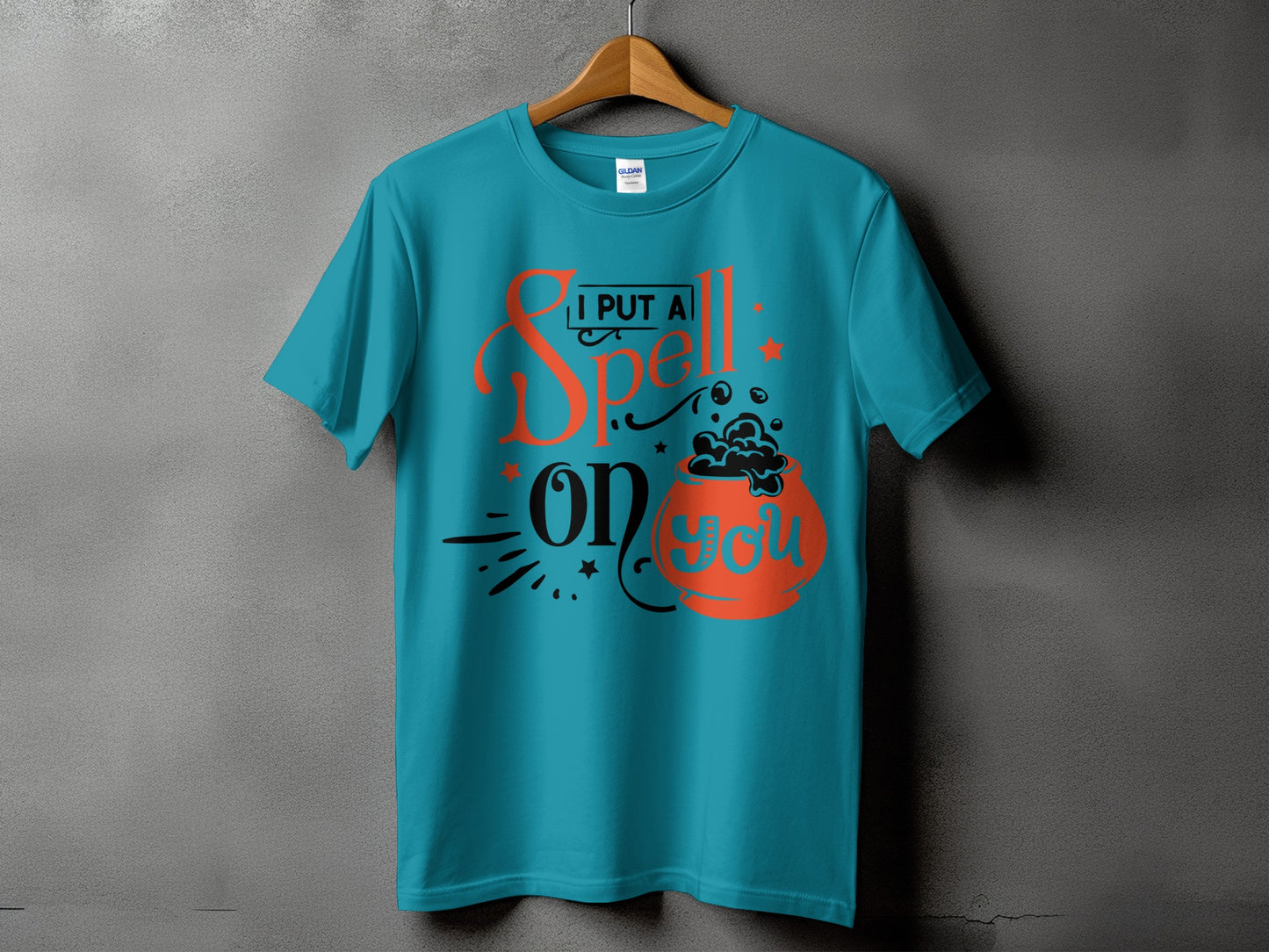 Teal t-shirt with orange and black text reading "I PUT A Spell on you" and a cauldron.