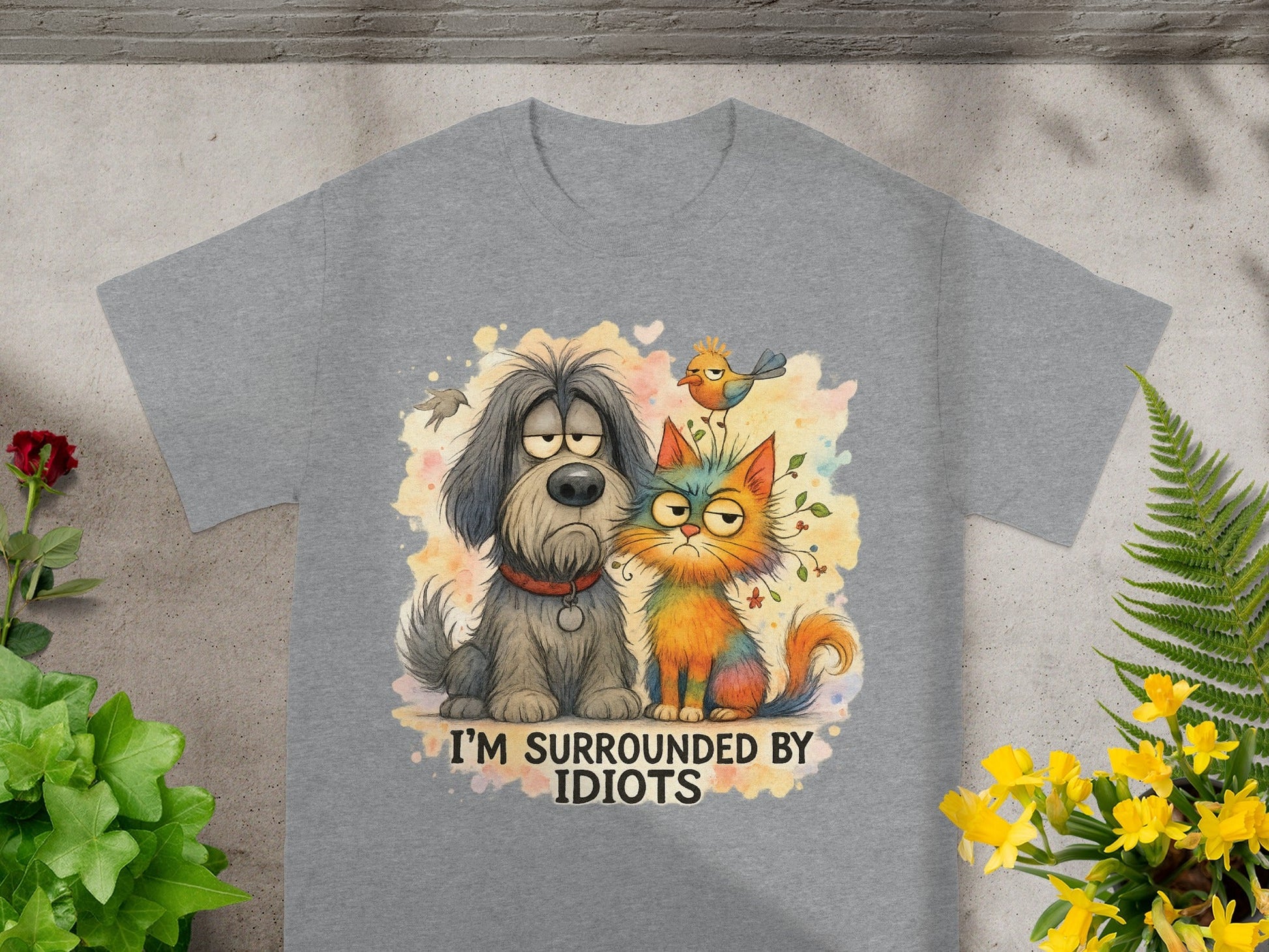 Grey t-shirt with cartoon dog, cat, and bird illustration reading "I'M SURROUNDED BY IDIOTS".
