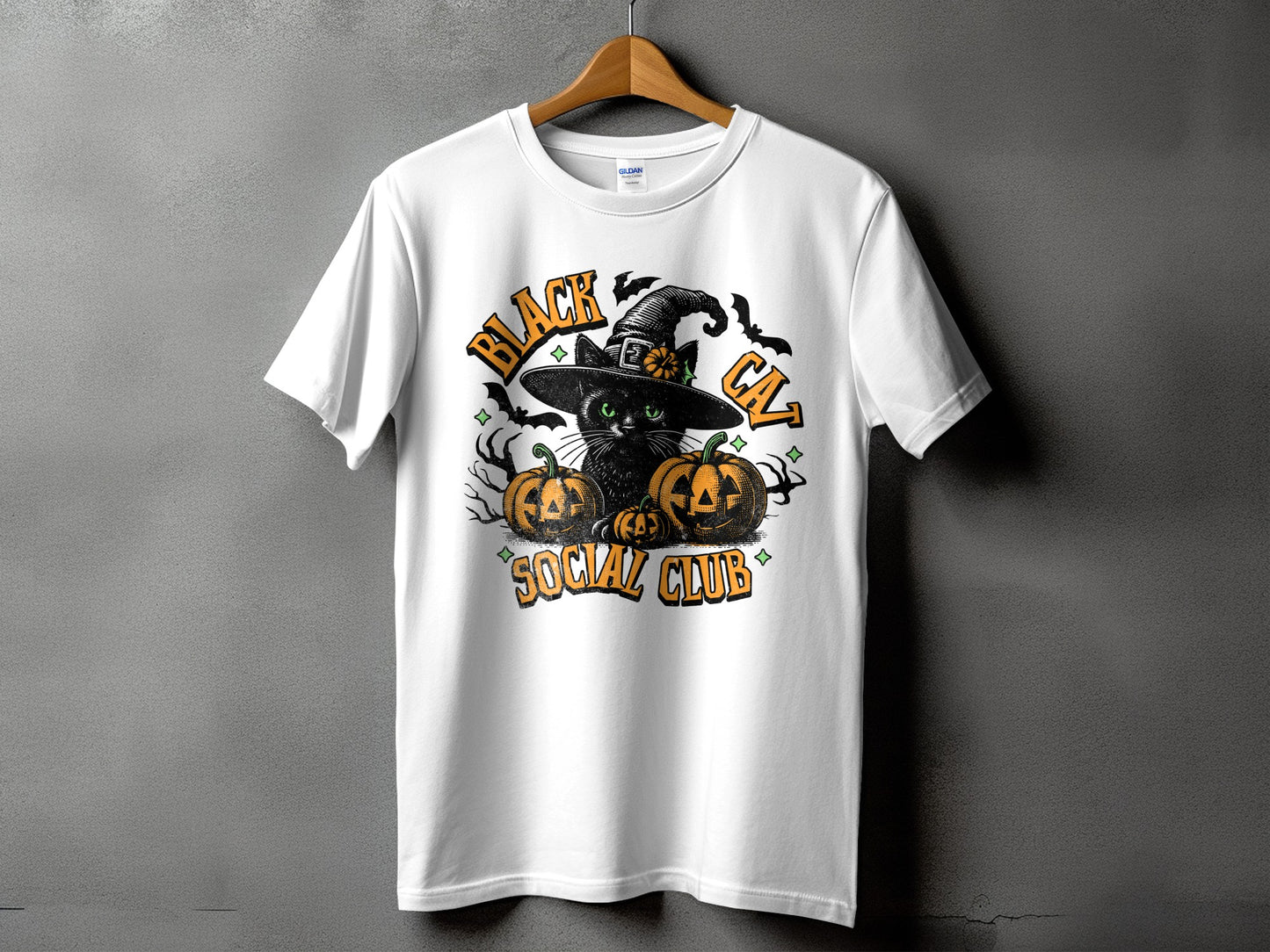 White t-shirt with a black cat wearing a witch hat and pumpkins, text reads "Black Cat Social Club".