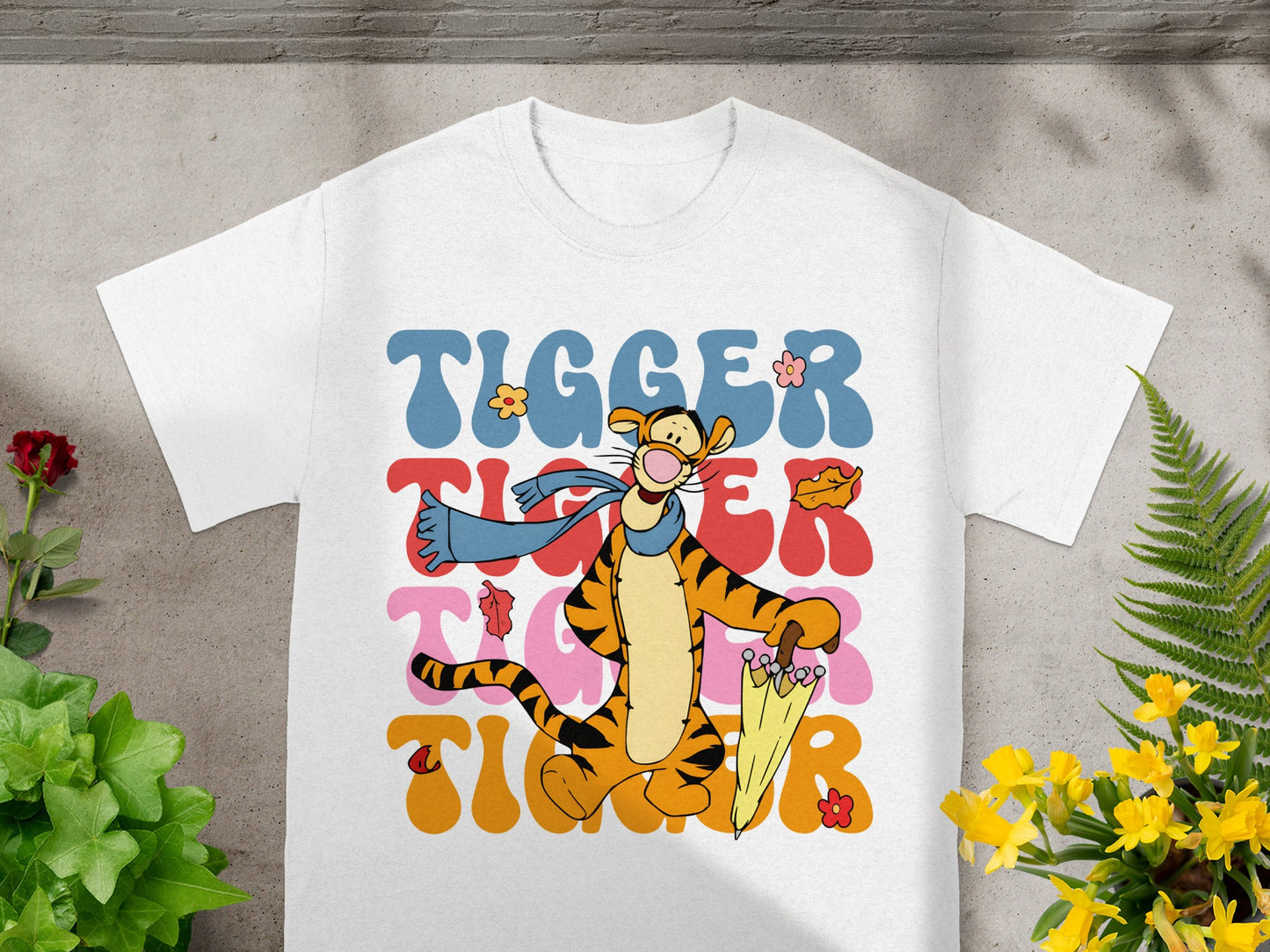 Tigger graphic on white t-shirt with yellow umbrella and colorful text.