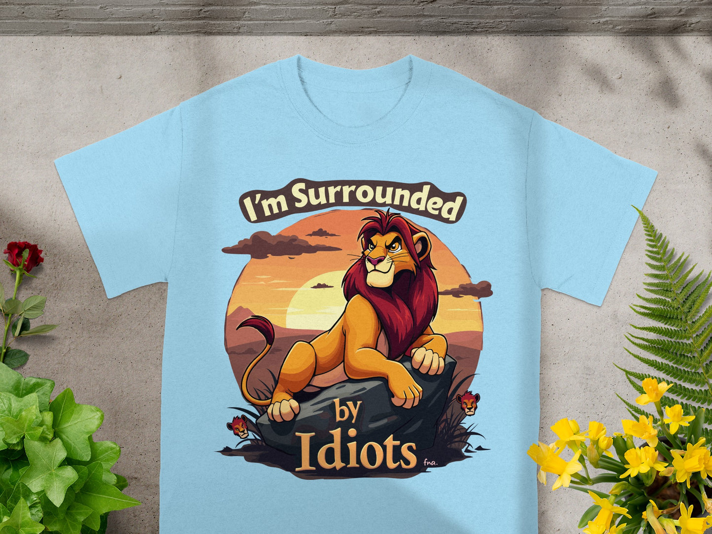 Light blue t-shirt with a lion graphic and text "I'm Surrounded by Idiots."
