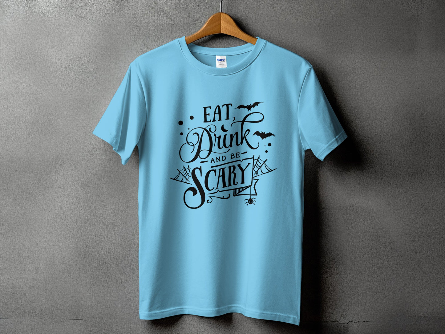 Light blue t-shirt with black Halloween text and graphics that read "Eat, Drink and be Scary".
