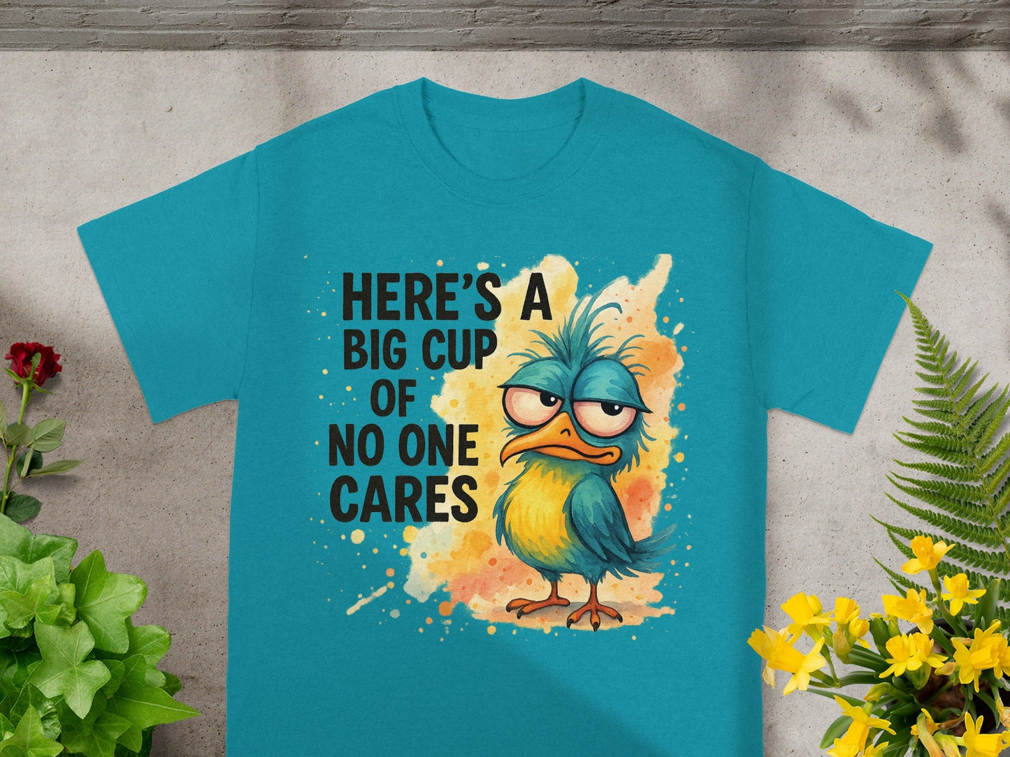 Teal t-shirt with cartoon bird and text "Here's a big cup of no one cares."