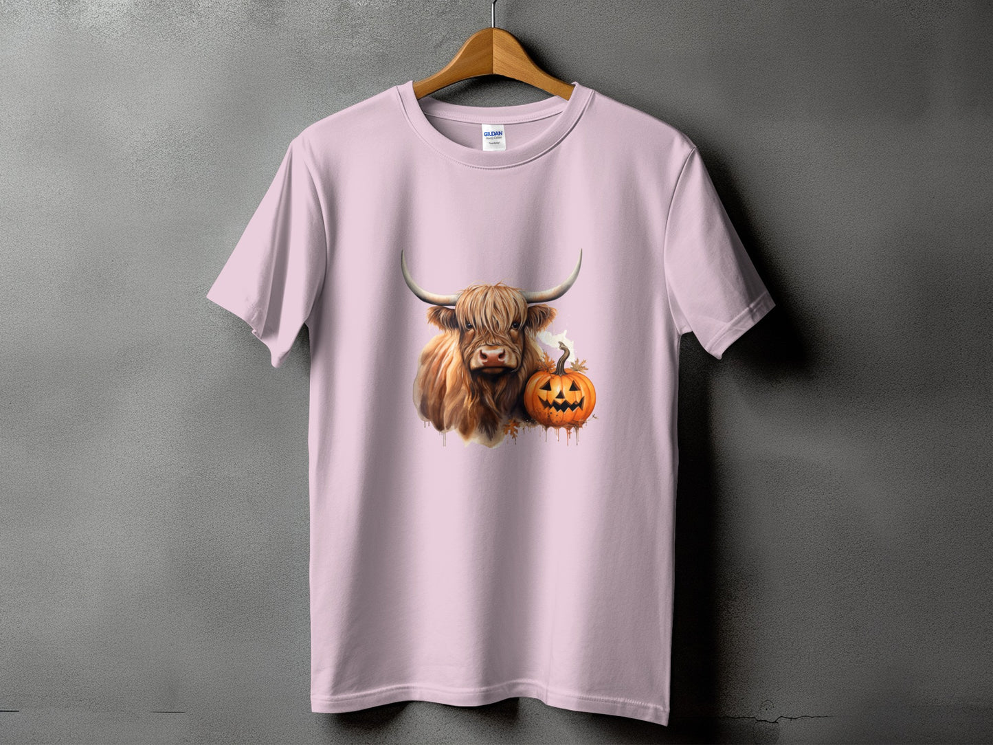 Pink t-shirt with a Highland cow and a carved pumpkin graphic.