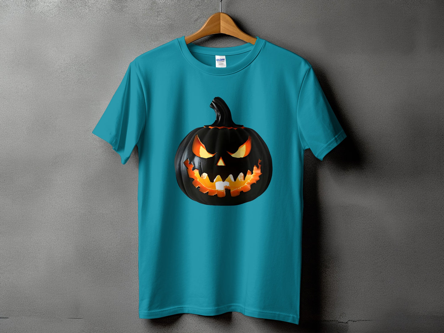 Teal t-shirt with a black jack-o'-lantern graphic featuring glowing yellow eyes and an orange mouth.