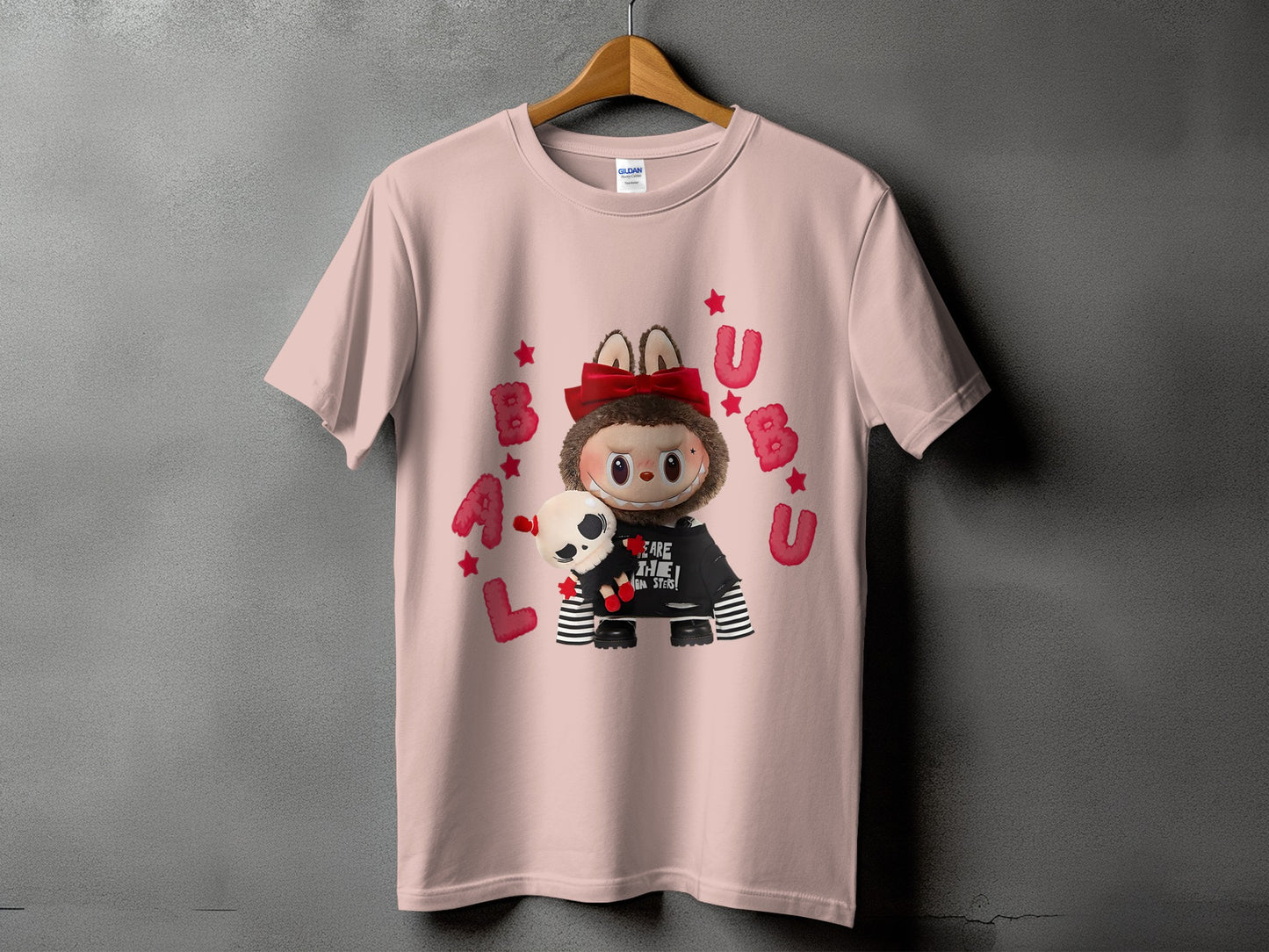 Pink t-shirt with a cute character holding a skull, surrounded by red stars and letters.