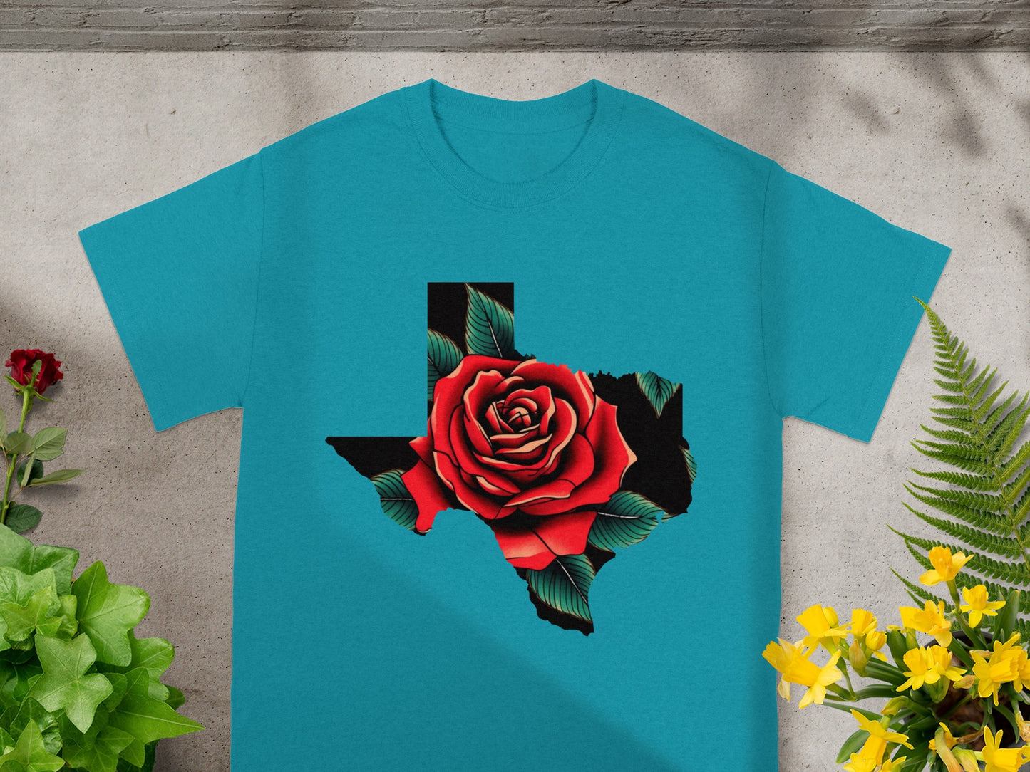 Teal t-shirt with Texas shape filled by a red rose and green leaves.