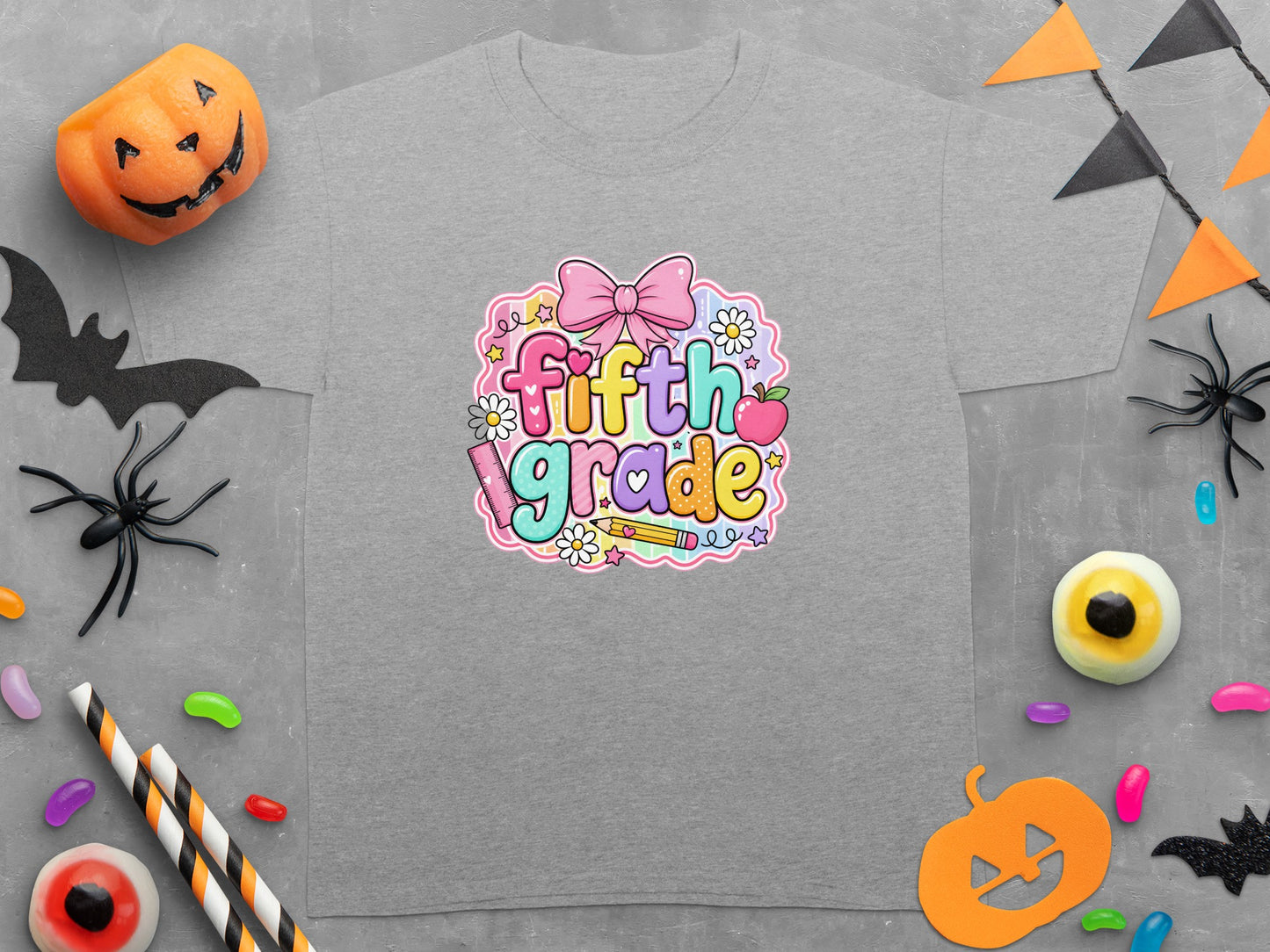Grey t-shirt featuring "fifth grade" in colorful, bubbly text with a bow and apple.